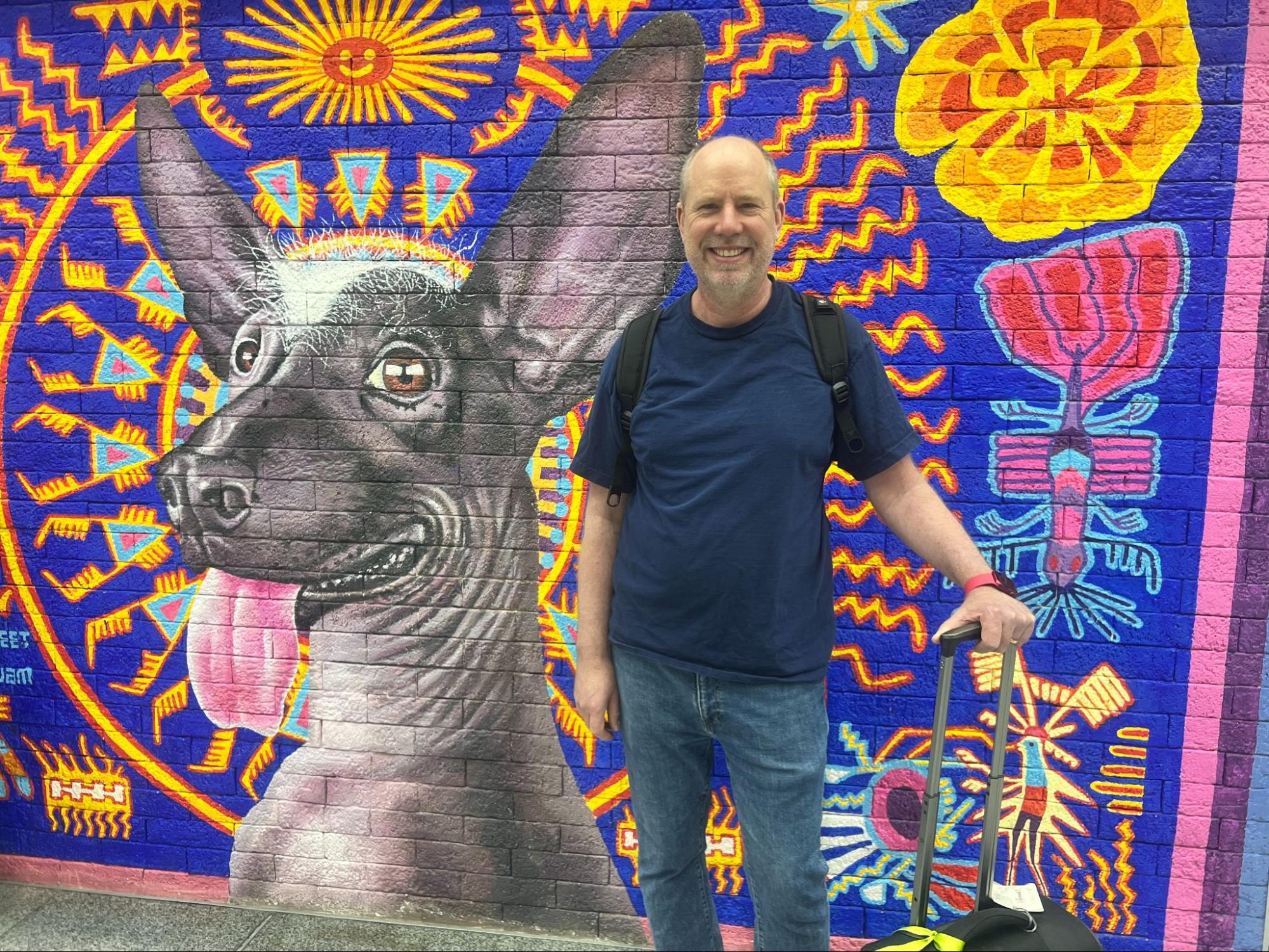 Andreas Oesterer standing beside a colorful mural in Mexico City